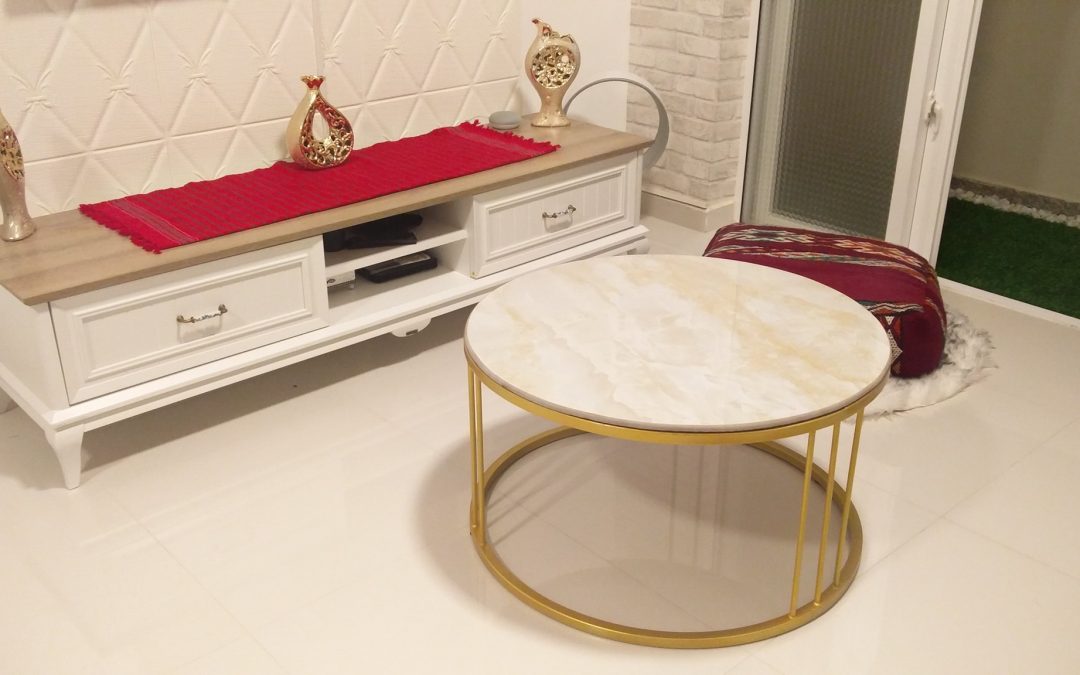 Substantial in size yet delicate in appearance, Akbar Coffee Table features a beige top with a bronze hourglass metal fretwork base that is a beautiful combination of size and grace.